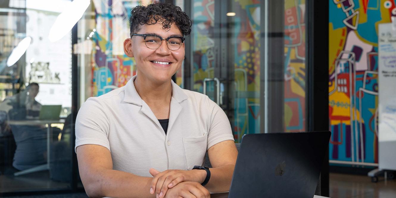 CU Denver student sitting at table working on laptop