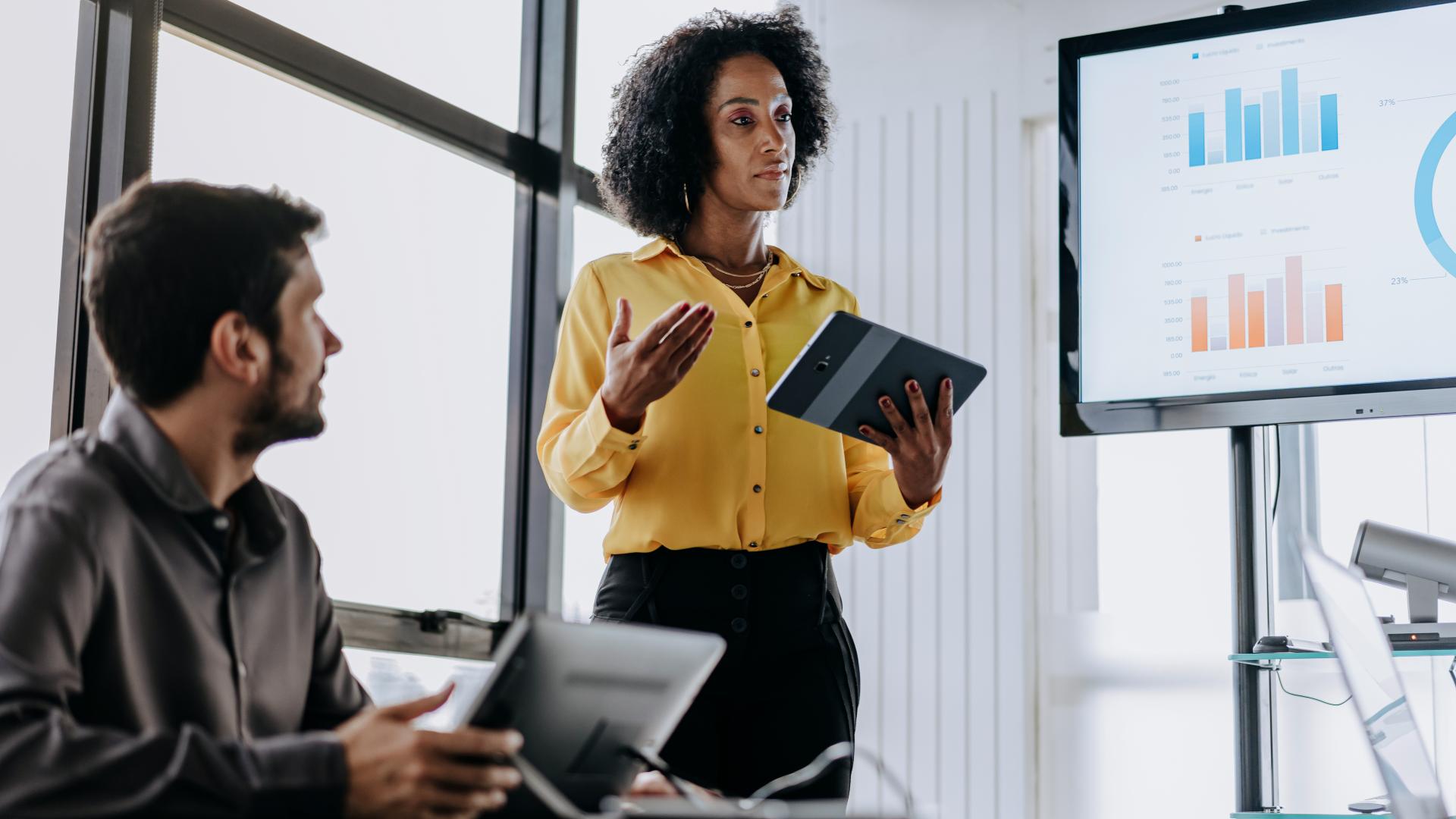 Business woman presenting financial results holding a digital tablet