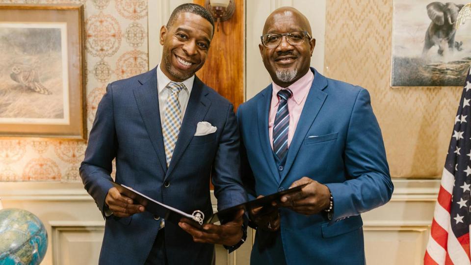 Two men in blue suits holding binder with notes from urban planning meeting