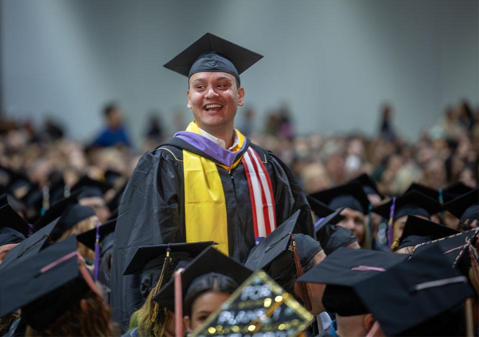 CU Denver graduate smiling in the commencement crowd
